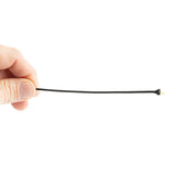A hand holds a thin, black Kevlar aramid fiber with a polyester sheath. The fiber is taut, with a small, yellow core visible through the black sheath at one end. The background is completely white.